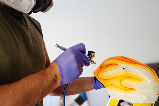 Close up of painter's hands painting flames on helmet.