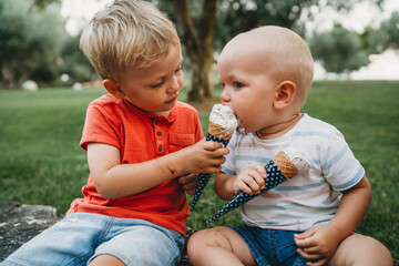 Boy sharing his ice cream with his little brother