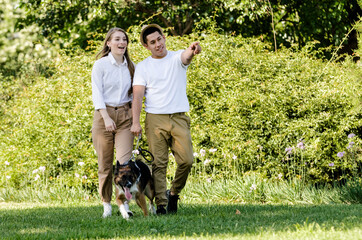 Naklejka na ściany i meble Young and modern couple walking and playing with their dog Border Collie in a park