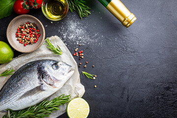 Fresh ready to cook raw bream fish dorado with ingredients and seasonings like rosemary, salt, pepper, lime and olive oil, top view