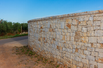 View of a country road with trees and stone wall