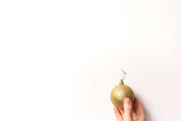 Christmas tree toy in hand isolated on a white background. New year glitter ball of gold color. Festive banner with place for text in fashion style.