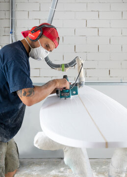 Surfboard shaper workshop - man checking quality of surfboard