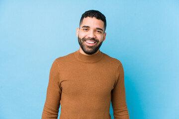 Young latin man against a blue  background isolated happy, smiling and cheerful.