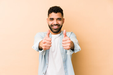 Young mixed race arabic man isolated with thumbs ups, cheers about something, support and respect concept.