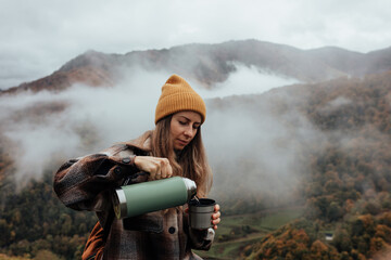 Portrait of woman traveling and exploring nature, preparing tea in a high place.