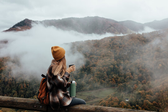 Portrait of woman traveling and exploring nature, preparing tea in a high place.