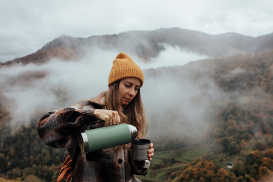 Portrait of woman traveling and exploring nature, preparing tea in a high place.