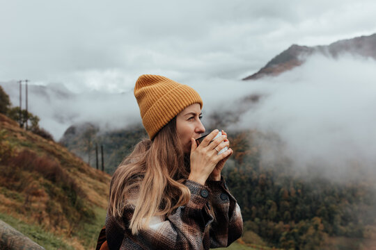 Portrait of woman traveling and exploring nature, preparing tea in a high place.
