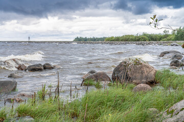 Fototapeta na wymiar Big wet stones in waves on lake shore