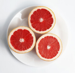 Fresh Red Grapefruits on a white plate. White background. Top view