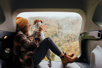 Portrait of a woman with her dog resting from a long trip in the trunk of her car.