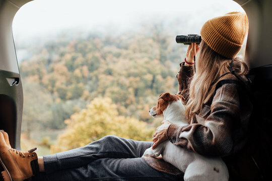 Portrait of a woman with her dog resting from a long trip in the trunk of her car.