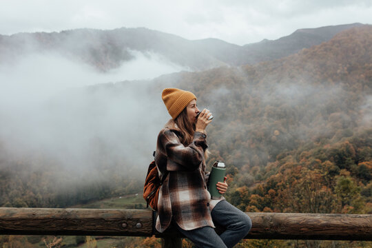 Portrait of woman traveling and exploring nature, preparing tea in a high place.