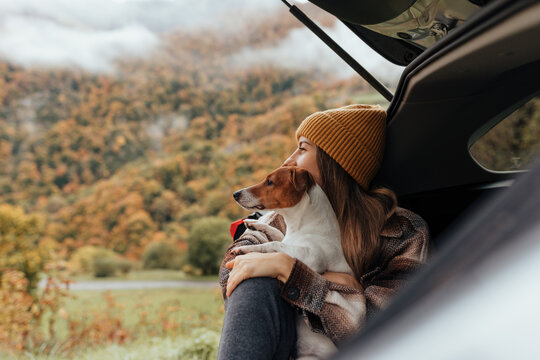 Portrait of a woman with her dog resting from a long trip in the trunk of her car.