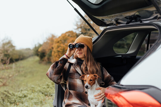 Portrait of a woman with her dog resting from a long trip in the trunk of her car.