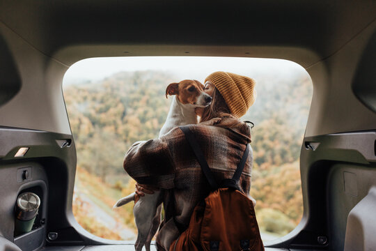 Portrait of a woman with her dog resting from a long trip in the trunk of her car.