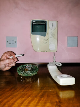Adult Hand Man Using a 90s Intercom While is Smoking a Cigarette Against a Pink Wall . Waiting and Obsession Concept