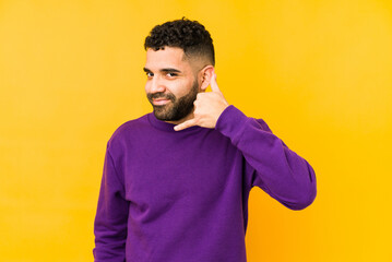 Young mixed race arabic man isolated showing a mobile phone call gesture with fingers.