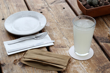 
New normal in restaurants, view rustic wooden table with plate and cutlery accompanied protection mask and antibacterial gel
