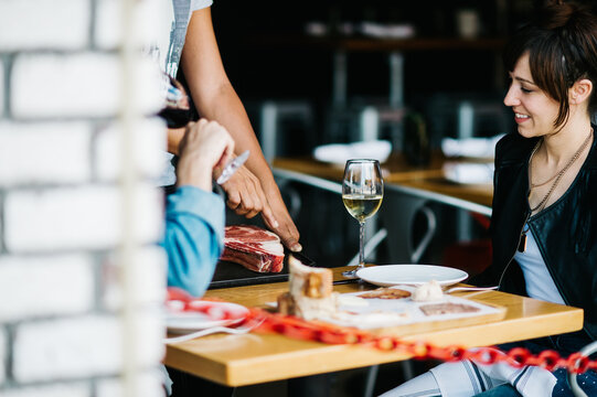 Restaurant patrons having meat options explained by server