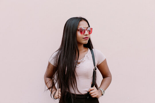 Portrait of a young Sri Lankan woman with backpack on pink background