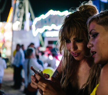 Two friends looking at mobile phone at night.
