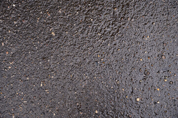 Abstract background of black wet asphalt with inclusions of pebbles