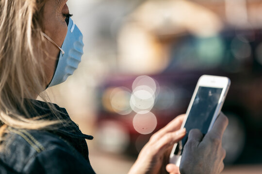 Virus: Woman Wearing N95 Mask Using Cell Phone - Powered by Adobe