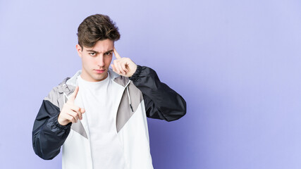 Young caucasian man isolated on purple background pointing temple with finger, thinking, focused on a task.