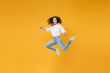 Fototapeta na wymiar Cheerful young brunette business woman in white shirt posing isolated on yellow background in studio. Achievement career wealth business concept. Mock up copy space. Jumping, spreading hands and legs.