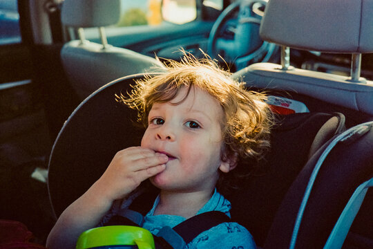 Cute Boy In Carseat Eating Snacks