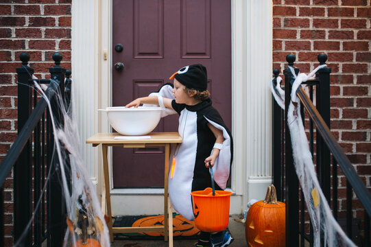 Preschooler trick or treater reaching into a left out candy bowl