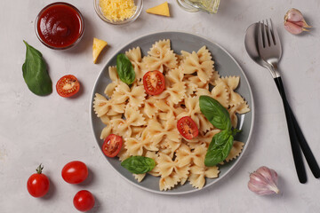 Farfalle pasta with cherry tomatoes, tomato sauce and basil on white background, close up, View from above