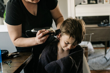 Boy expresses displeasure with having his mother clipper his hair