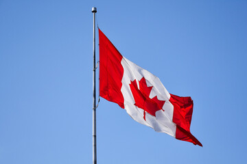 canadian flag waving against blue sky