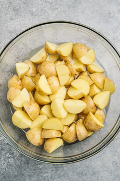 Quartered new potato wedges soaking in a mixing bowl