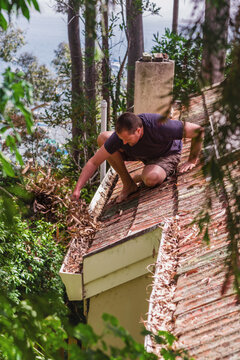 man clearing leaves off roof