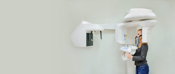 Young woman in a dental 3D x-ray digital scanner panorama machine in clinic.