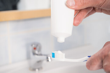 Fototapeta premium Person putting toothpaste on toothbrush