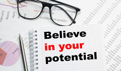 Business concept. Notebook with text Believe in your potential sheet of white paper for notes, calculator, glasses, pencil, pen, in the white background