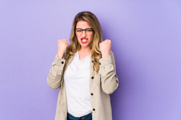 Fototapeta premium Young caucasian woman isolated on purple background upset screaming with tense hands.