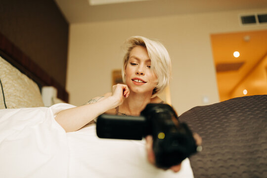 young blond woman with small camcorder on the bed