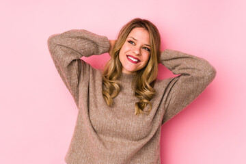 Young caucasian woman isolated on pink background feeling confident, with hands behind the head.