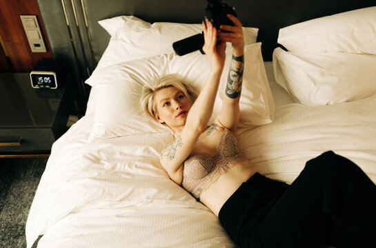 young blond woman with small camcorder on the bed