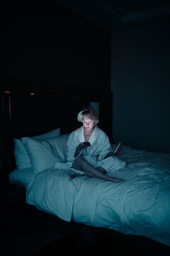 young woman with cell phone on the bed