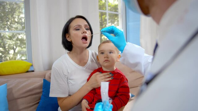 Children's doctor visiting little boy at home taking sample for analysis from mother
