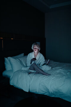 young woman with cell phone on the bed