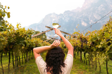 Young woman with a glass of white wine in the vineyards of Italy. Person pouring wine. Free space for text. High quality photo