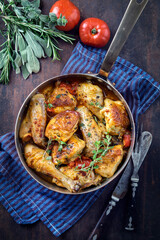 Traditional French lemon chicken in sauce with tomatoes offered as top view in a rustic casserole © HLPhoto